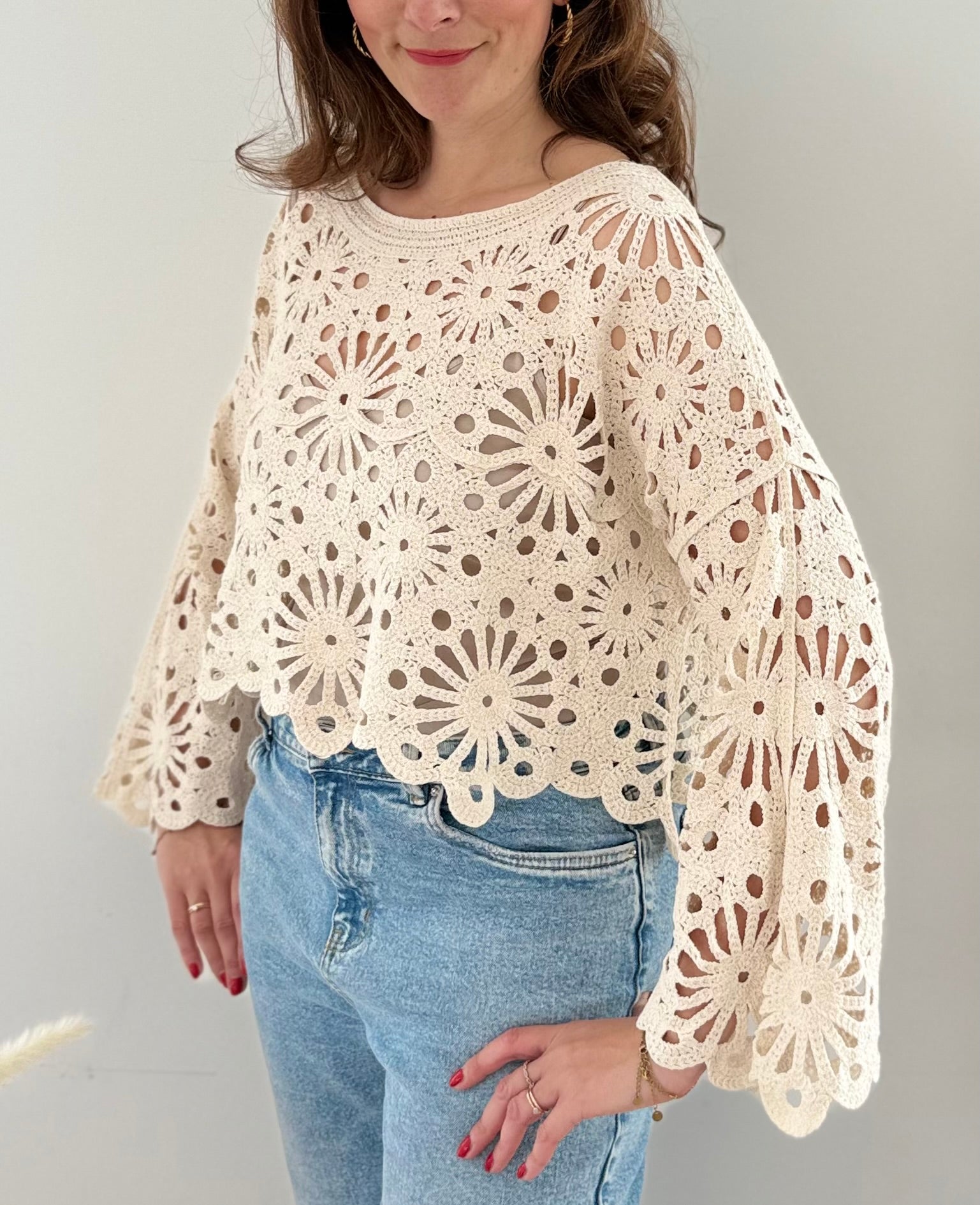 Kurzpullover mit verspieltem Blumenmuster in Häkeloptik. Die langen Schlagärmel runden den Boho Look perfekt ab. Der Pulli ist beige.