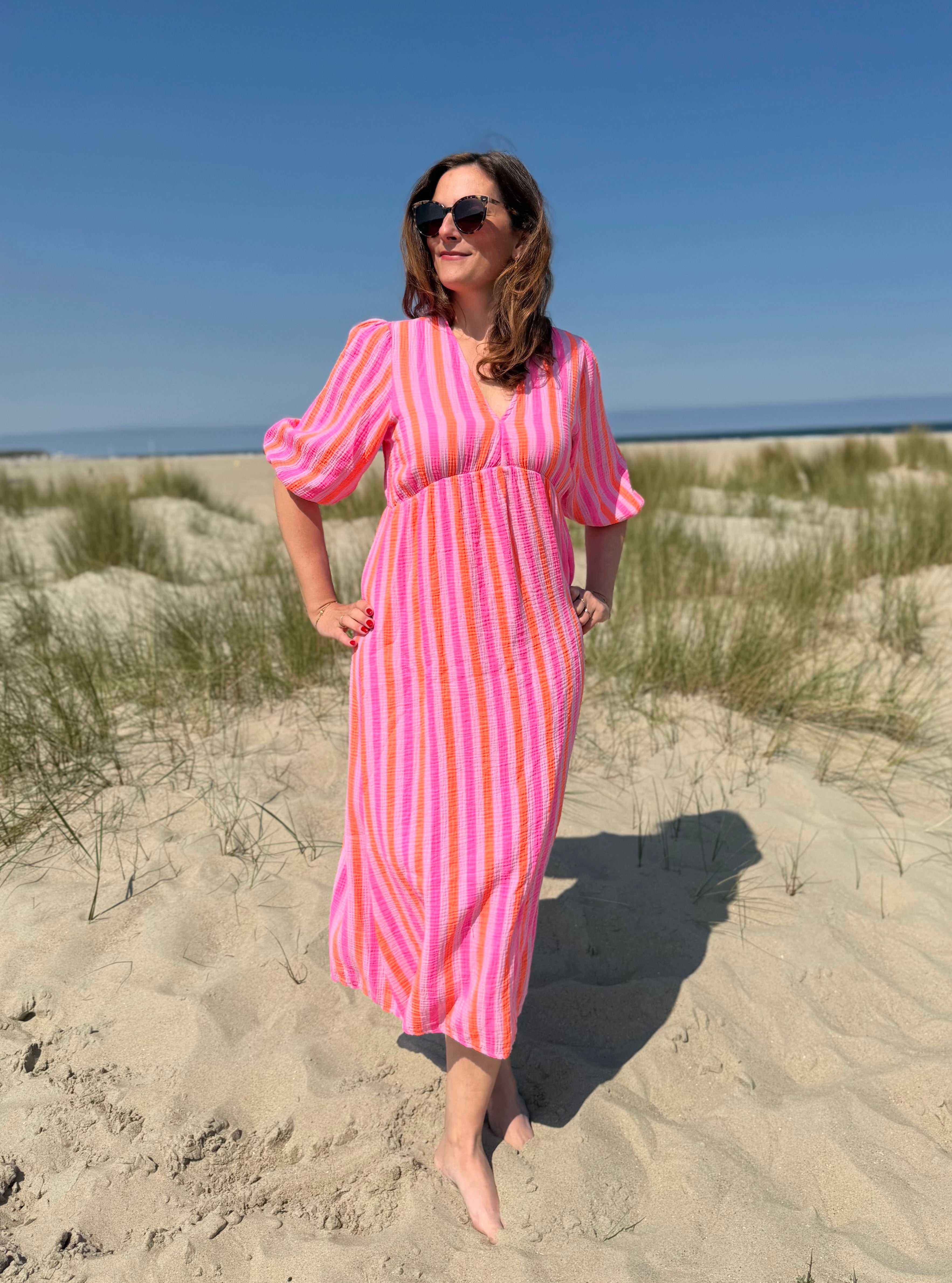 Leichtes langes Musselinkleid mit wunderschönem lockeren Schnitt. Das Kleid hat einen V-Ausschnitt und 3/4 lange Ärmel. Das Kleid ist pink, rosa, orange gestreift.