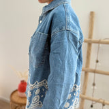 Verspielte blaue Jeansjacke im Oversize Look. Die wunderschöne weiße Lochstickerei mit Blumenmuster im unteren Bereich macht diese Jeansjacke zu einem ausgefallenen Lieblingsteil.