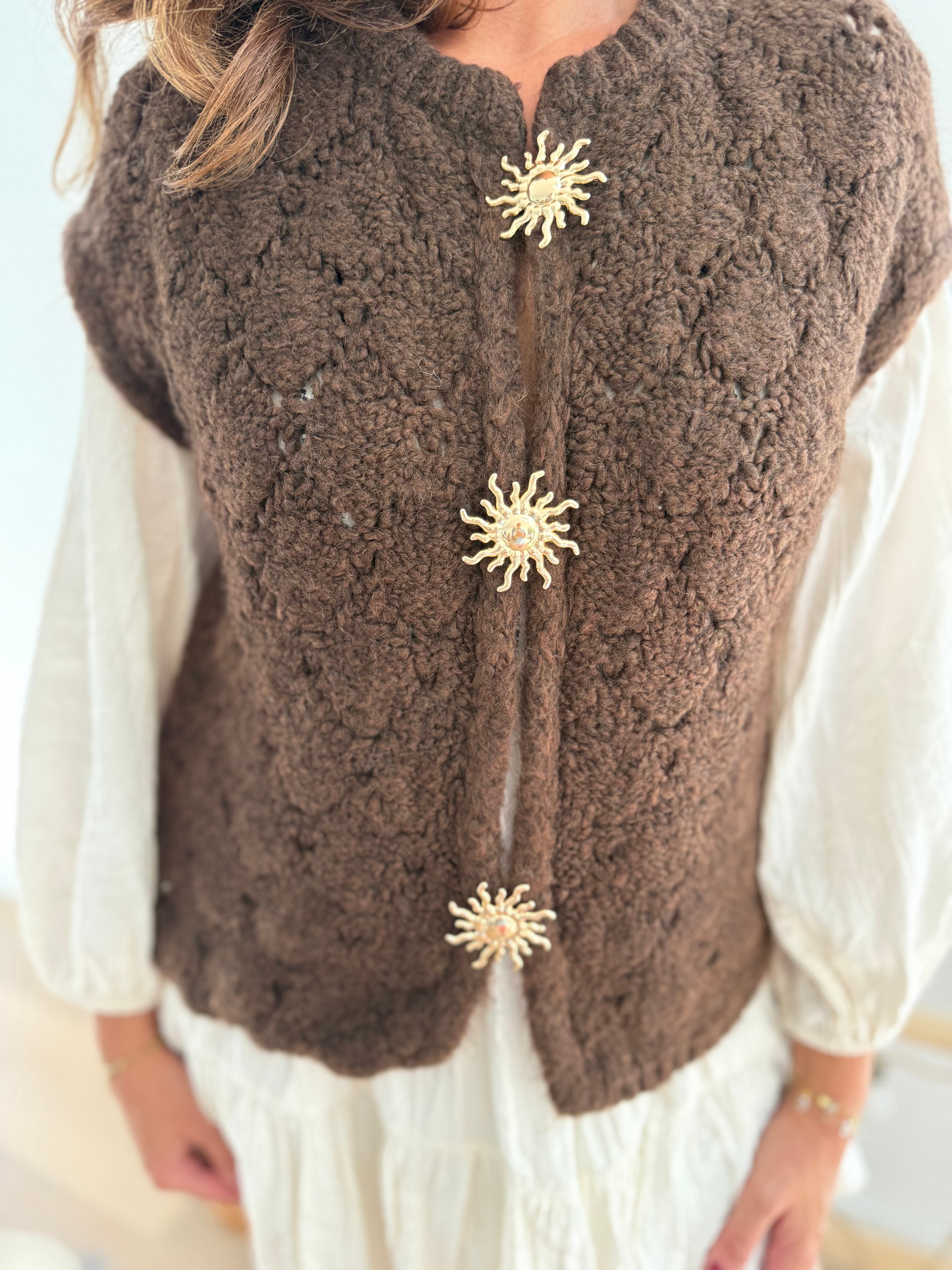 Kuschelige Strickweste in braun aus grobem Strick. Die Weste wird von 3 goldenen Sonnenbroschen zusammen gehalten.