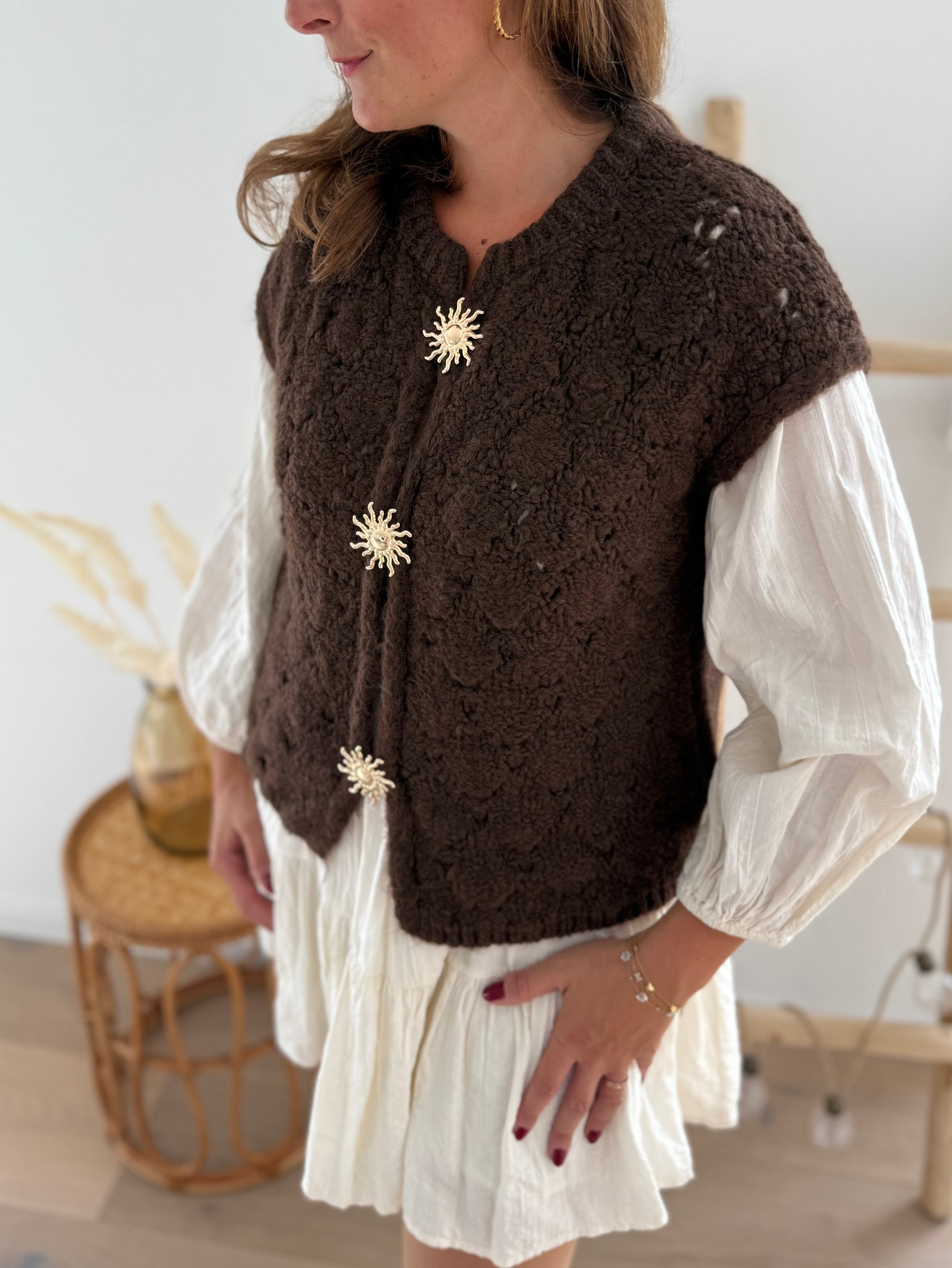 Kuschelige Strickweste in braun aus grobem Strick. Die Weste wird von 3 goldenen Sonnenbroschen zusammen gehalten.