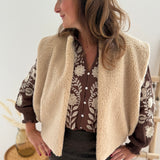 Kuschelige Teddyweste in beige. Die Weste hat einen lockeren kurzen Schnitt und wird ohne Knopfleiste offen getragen.
