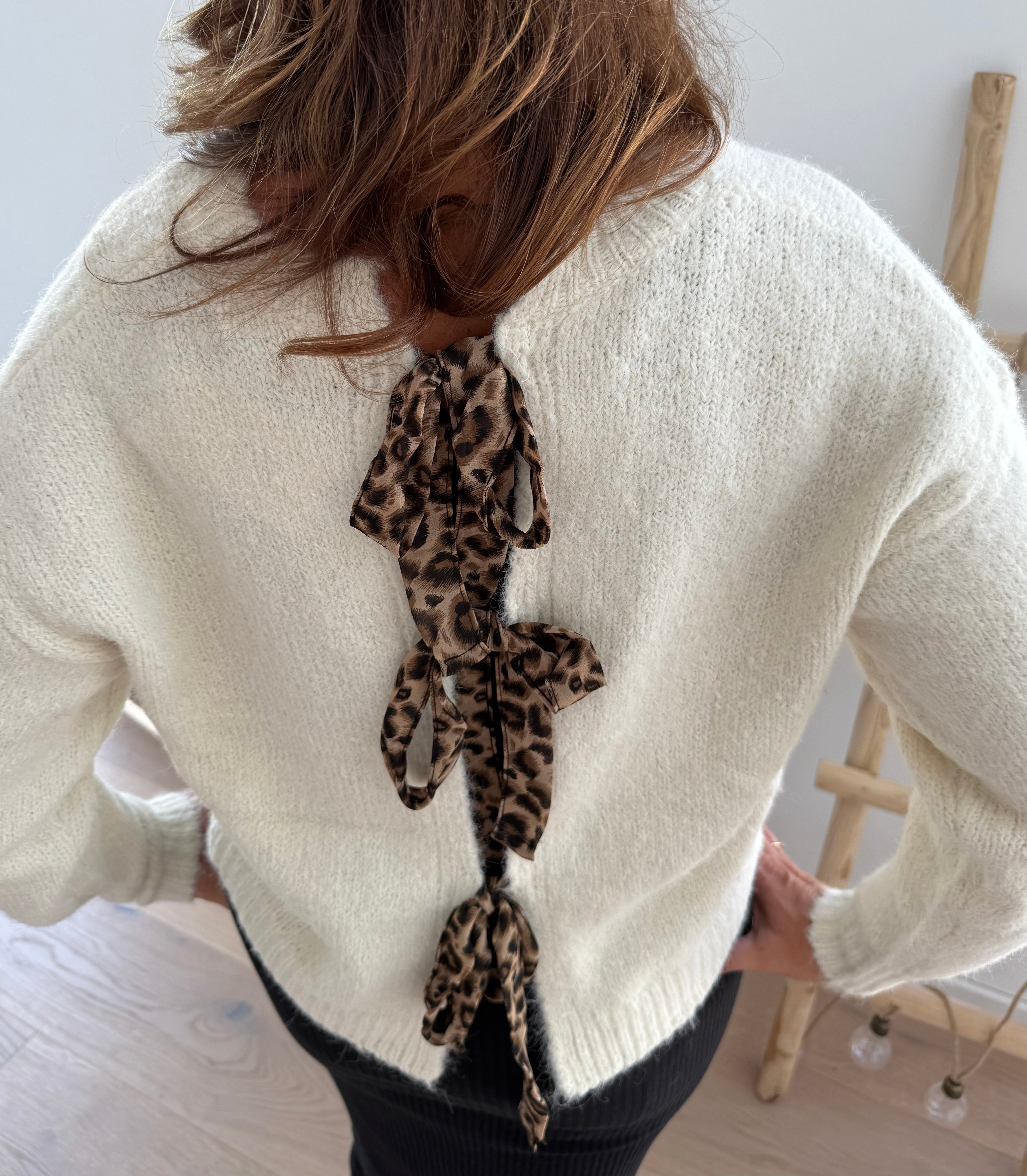 Strickpullover in beige mit Rundhalsausschnitt. Hinten wird der Pulli von Schleifen im Leoprint Muster zusammengehalten.