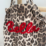 Große Shopper Bag aus strapazierfähigem Denim Stoff. Tasche ist in Leomuster mit rotem "Bella" Schriftzug aufgedruckt.