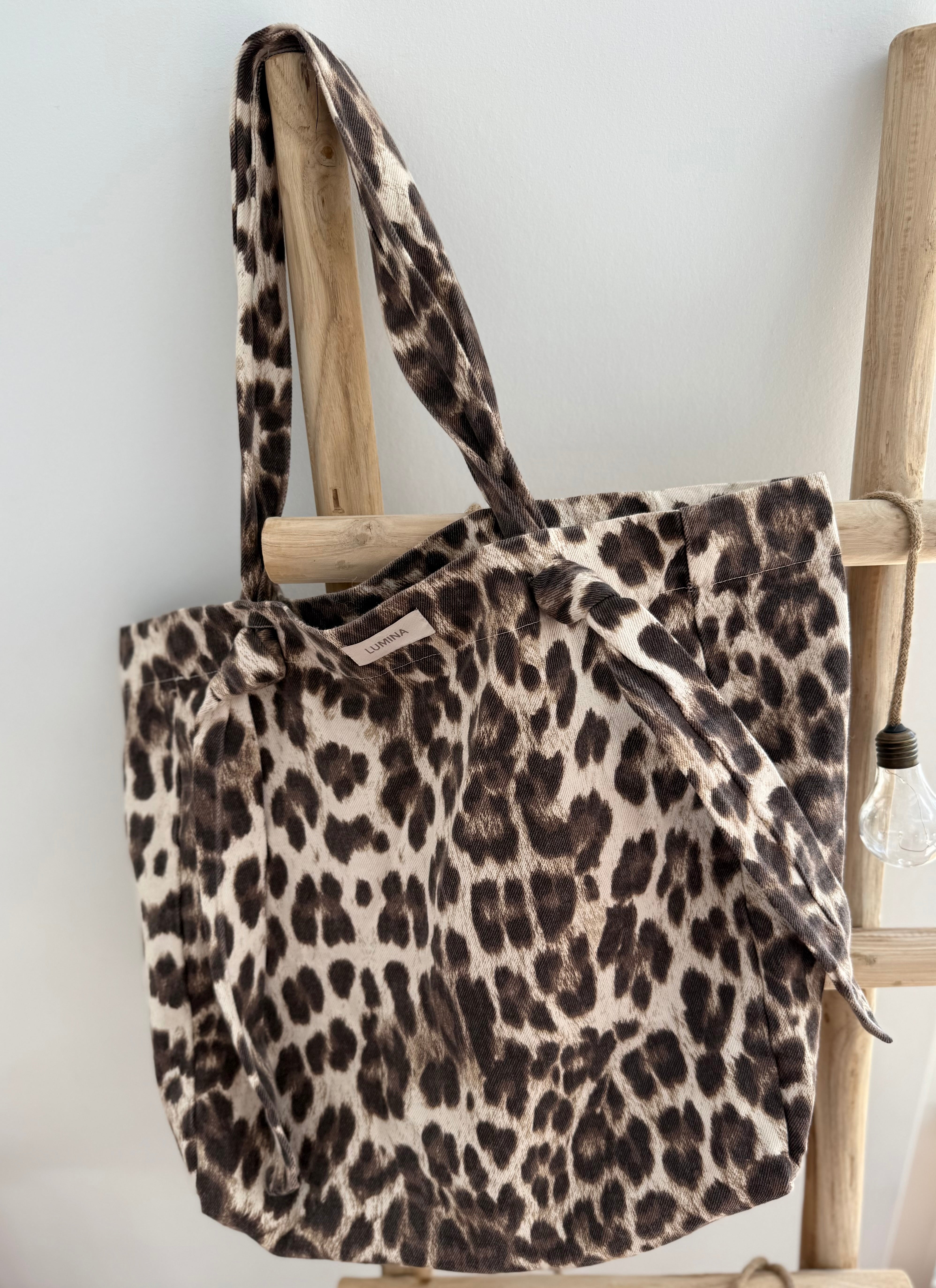 Große Shopper Bag aus strapazierfähigem Denim Stoff. Tasche ist in Leomuster mit rotem "Bella" Schriftzug aufgedruckt. Auf der Rückseite ist kein roter Schriftzug, sodass man die Tasche auch so herum tragen kann wenn rot gerade nicht zum Outfit passt.