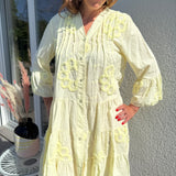 Luftiges kurzes Sommerkleid mit verspielter Blumen Beflockung. Das Kleid fällt locker leicht. Das Kleid hat eine Knopfleiste und einen V Ausschnitt. Die Ärmel sind 3/4 lang. Farbe hellgelb.