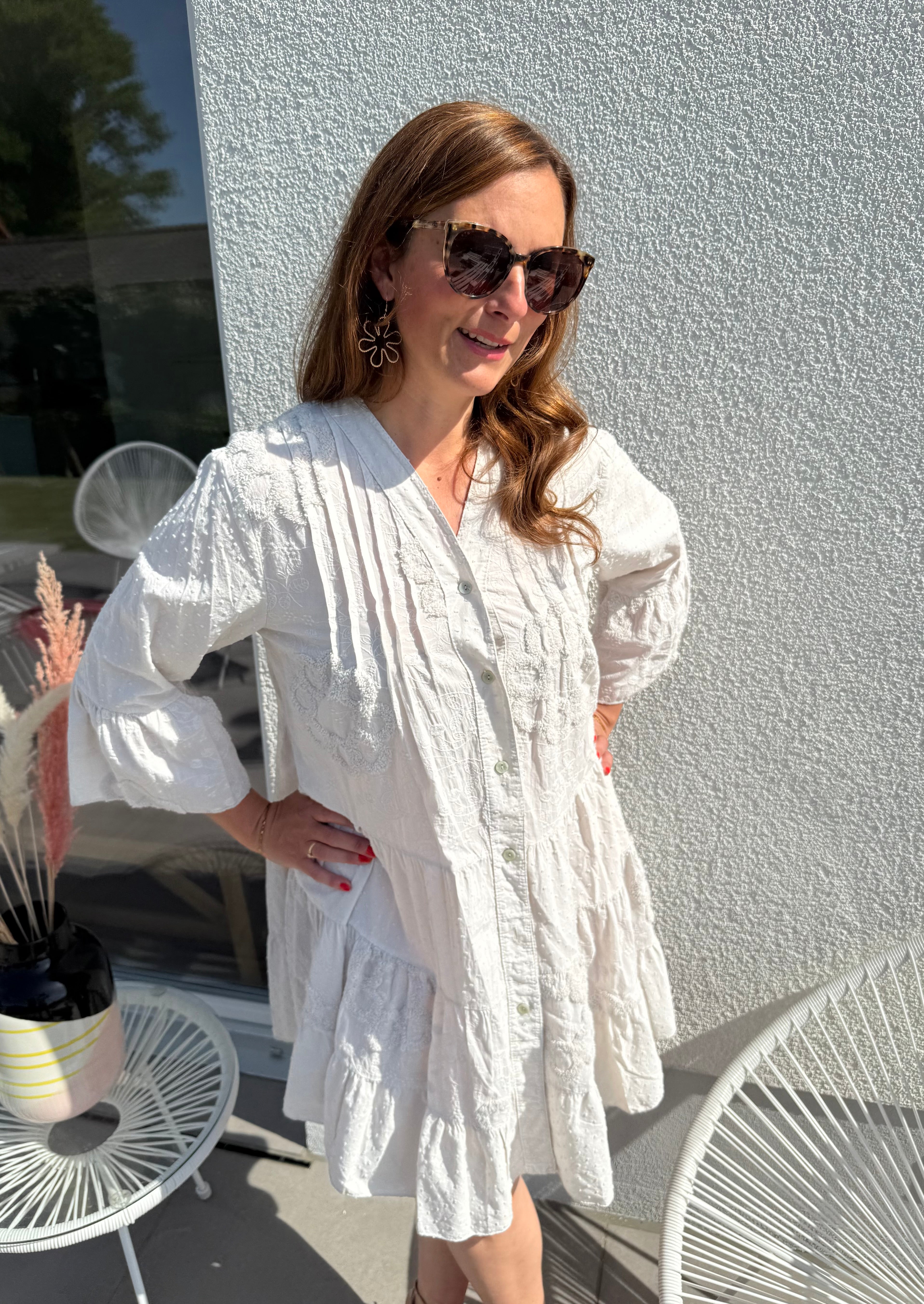 Luftiges kurzes Sommerkleid mit verspielter Blumen Beflockung. Das Kleid fällt locker leicht. Das Kleid hat eine Knopfleiste und einen V Ausschnitt. Die Ärmel sind 3/4 lang. Farbe beige.