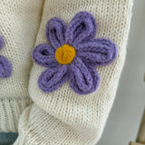 Statement Strickjacke in creme mit wunderschönen großen Blumenapplikationen in gelb und lila in Form einer Margerite . Die Strickjacke fällt locker und hat einen V Ausschnitt.