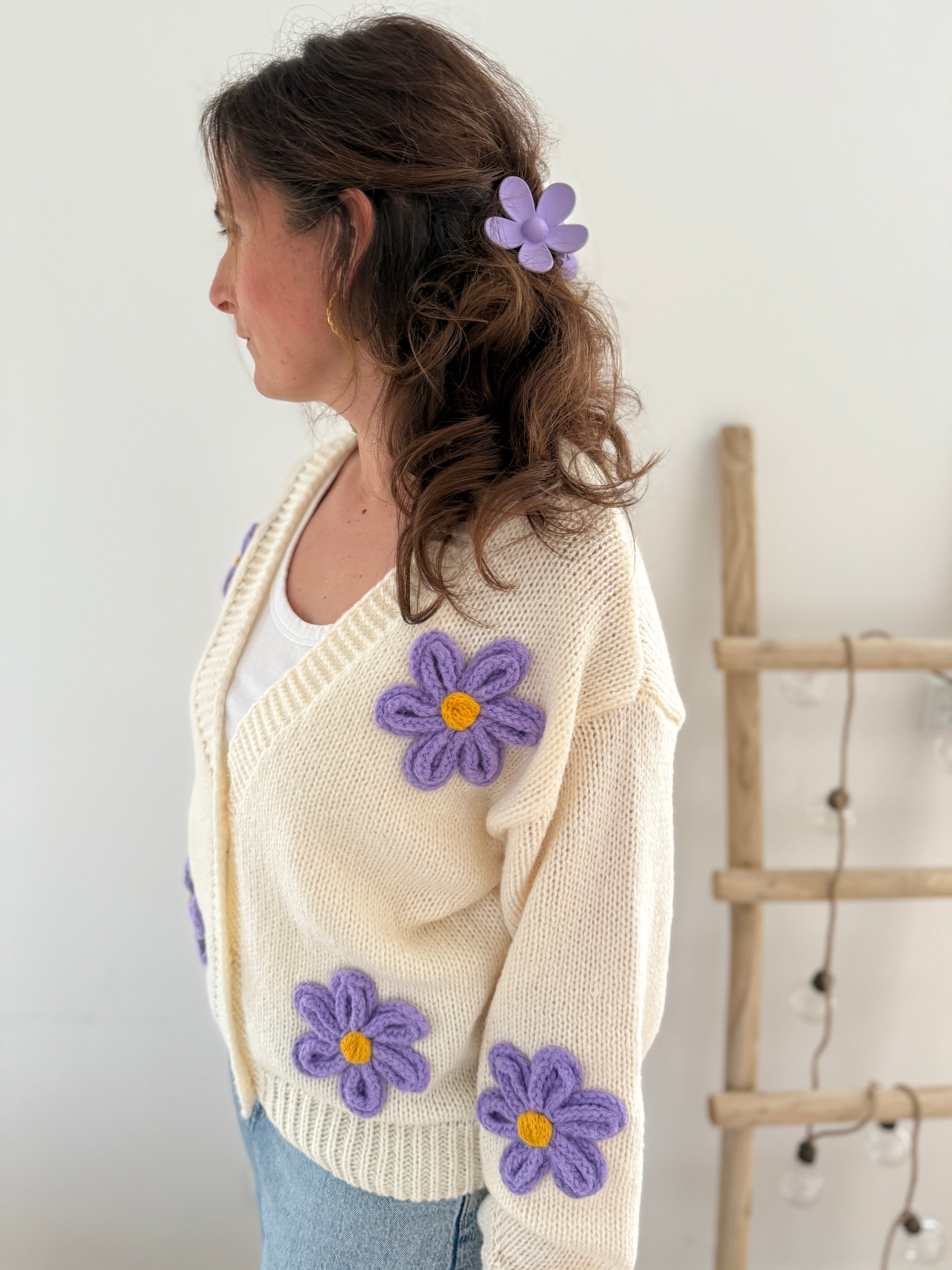 Statement Strickjacke in creme mit wunderschönen großen Blumenapplikationen in gelb und lila in Form einer Margerite . Die Strickjacke fällt locker und hat einen V Ausschnitt.