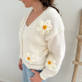 Statement Strickjacke in weiß mit wunderschönen großen Blumenapplikationen in gelb und weiß in Form einer Margerite . Die Strickjacke fällt locker und hat einen V Ausschnitt.