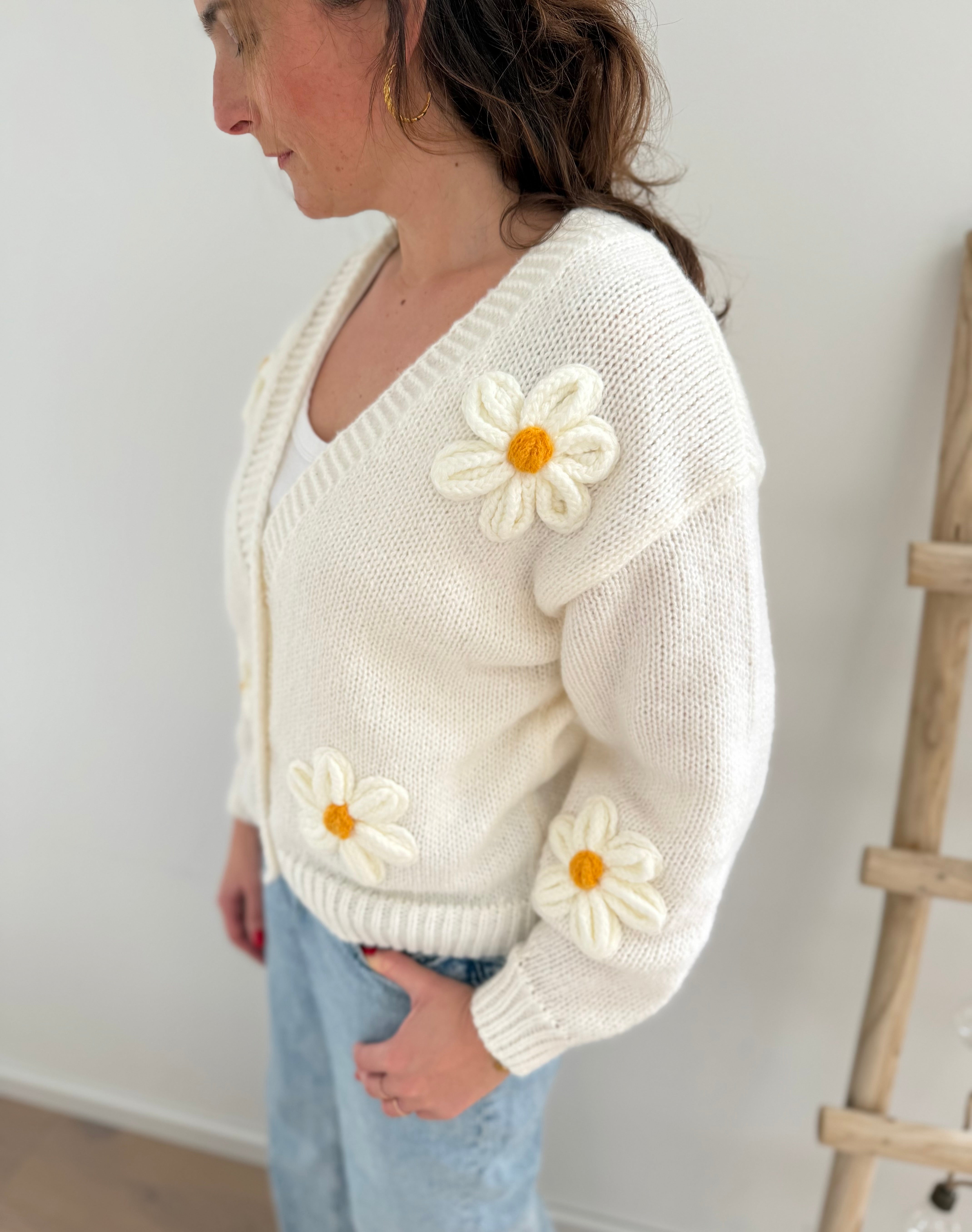 Statement Strickjacke in weiß mit wunderschönen großen Blumenapplikationen in gelb und weiß in Form einer Margerite . Die Strickjacke fällt locker und hat einen V Ausschnitt.