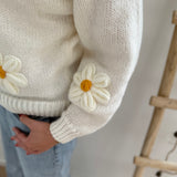 Statement Strickjacke in weiß mit wunderschönen großen Blumenapplikationen in gelb und weiß in Form einer Margerite . Die Strickjacke fällt locker und hat einen V Ausschnitt.