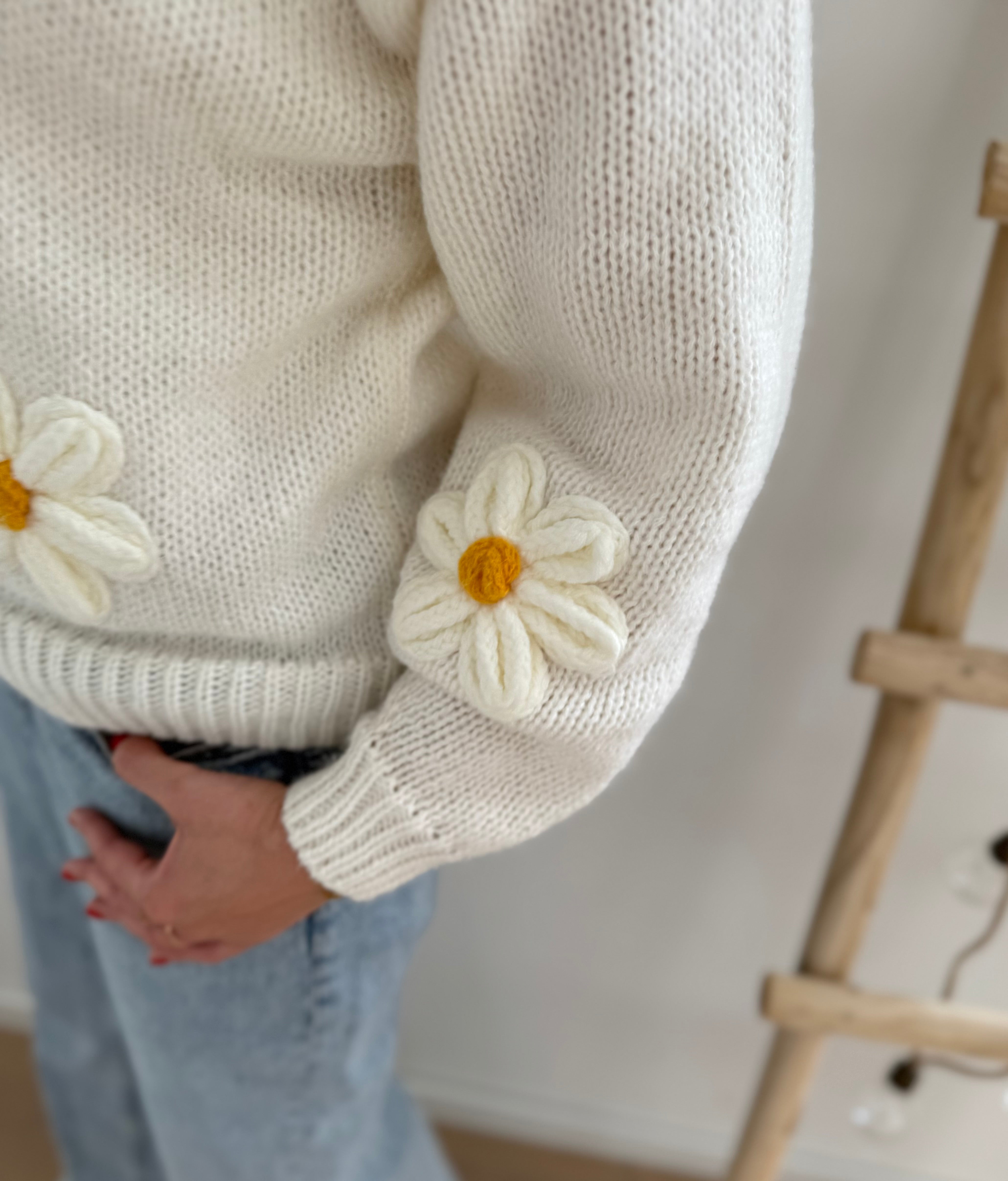 Statement Strickjacke in weiß mit wunderschönen großen Blumenapplikationen in gelb und weiß in Form einer Margerite . Die Strickjacke fällt locker und hat einen V Ausschnitt.