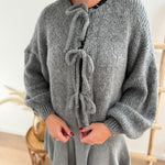 Locker fallende Strickjacke in grau die mit 3 Schleifen vorne zusammen gebunden wird.
