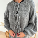 Locker fallende Strickjacke in grau die mit 3 Schleifen vorne zusammen gebunden wird.