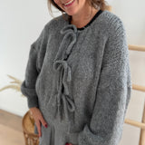 Locker fallende Strickjacke in grau die mit 3 Schleifen vorne zusammen gebunden wird.