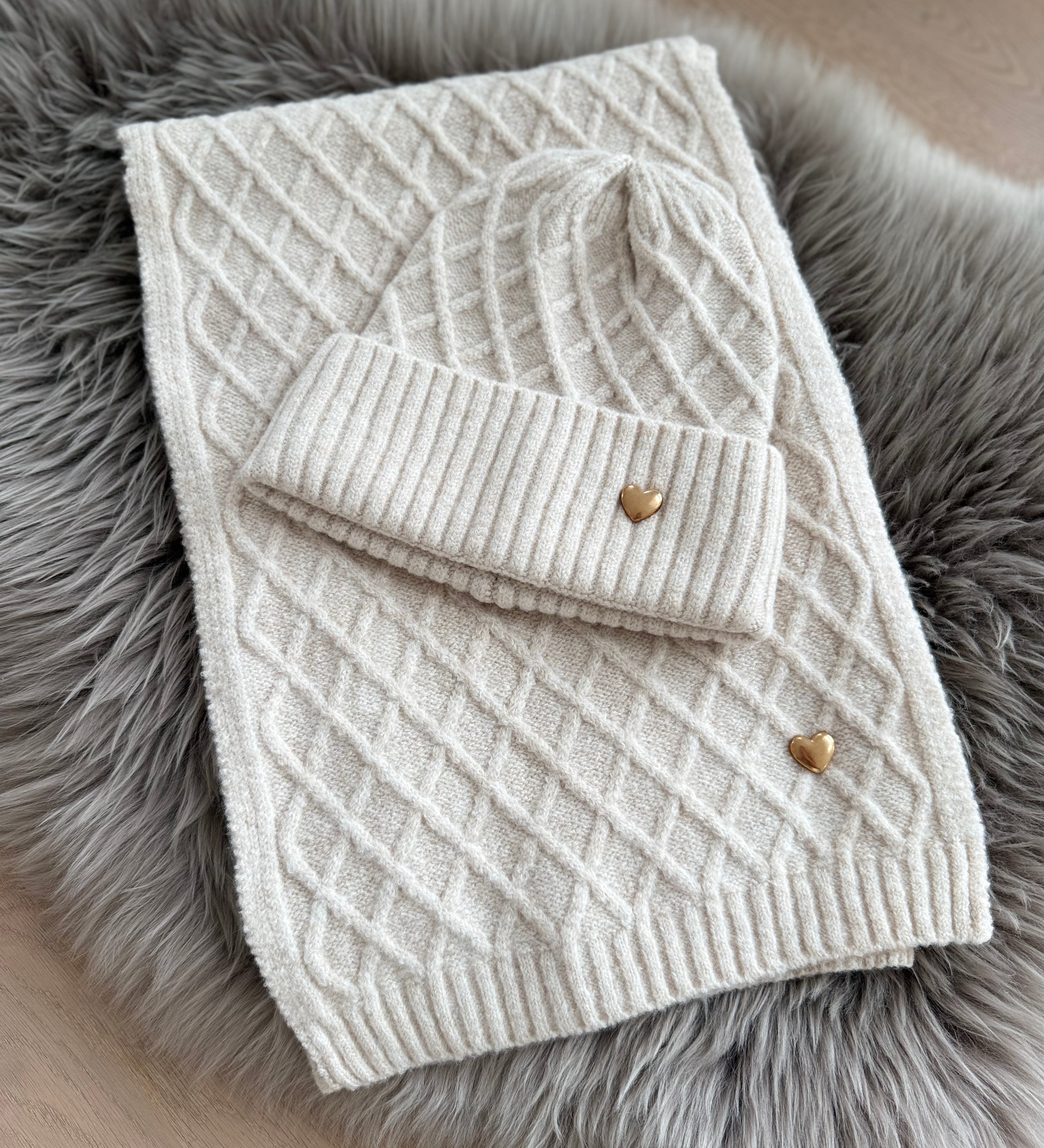 Beiges Schal & Mütze Set aus geflochtenem Strick mit kleiner goldenen Herzapplikation.
