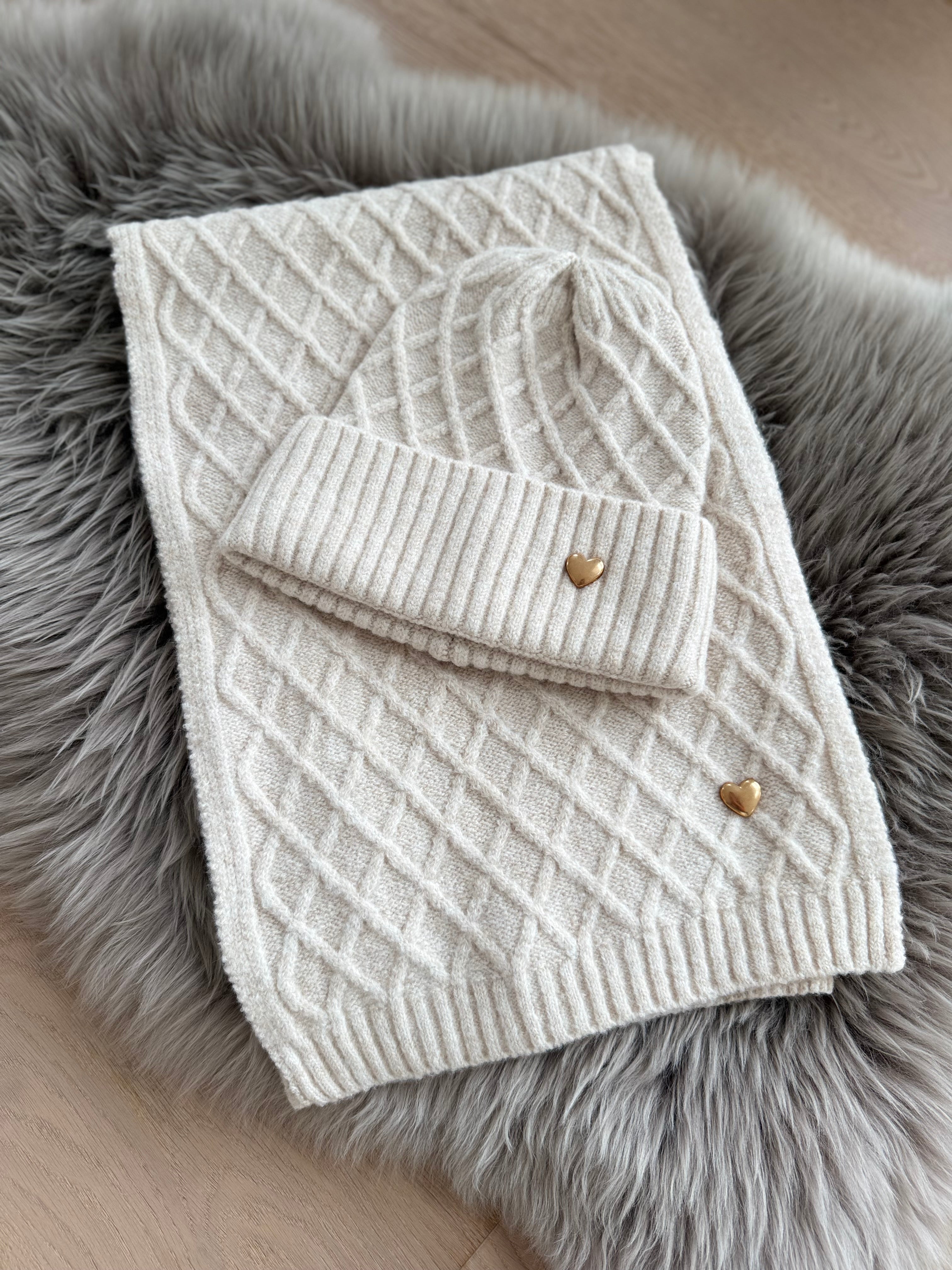 Beiges Schal & Mütze Set aus geflochtenem Strick mit kleiner goldenen Herzapplikation.