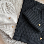 Set Schal & Mütze aus geflochtenem Strick mit kleiner goldenen Herzapplikation.