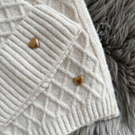 Beiges Schal & Mütze Set aus geflochtenem Strick mit kleiner goldenen Herzapplikation.