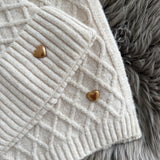 Beiges Schal & Mütze Set aus geflochtenem Strick mit kleiner goldenen Herzapplikation.