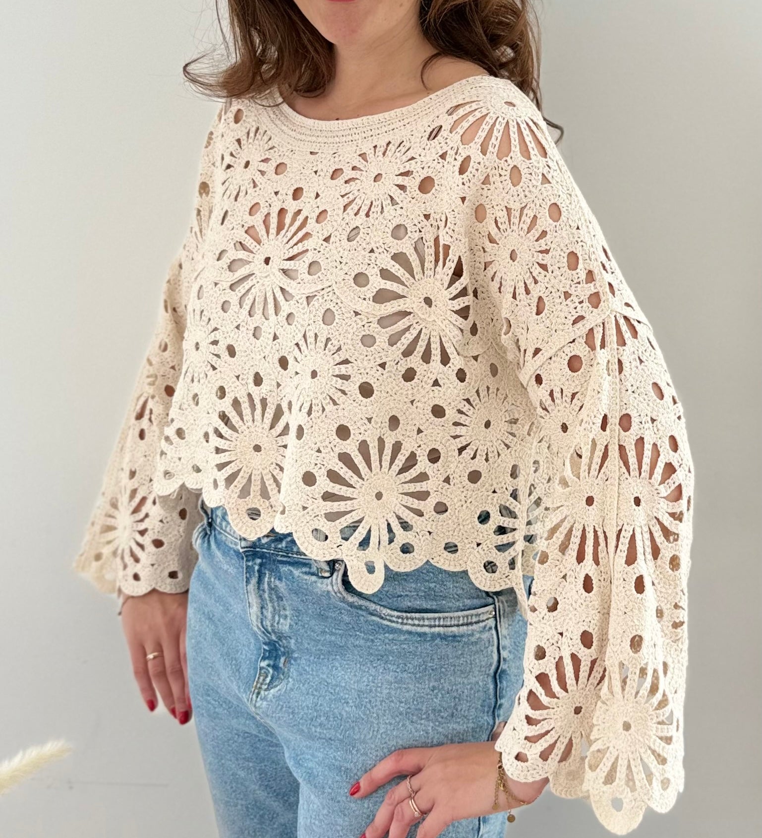 Kurzpullover mit verspieltem Blumenmuster in Häkeloptik. Die langen Schlagärmel runden den Boho Look perfekt ab. Der Pulli ist beige.