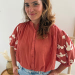 Leichte locker sitzende Baumwollbluse in rostrot mit beigen Blumenstickereien an den Ärmeln.
