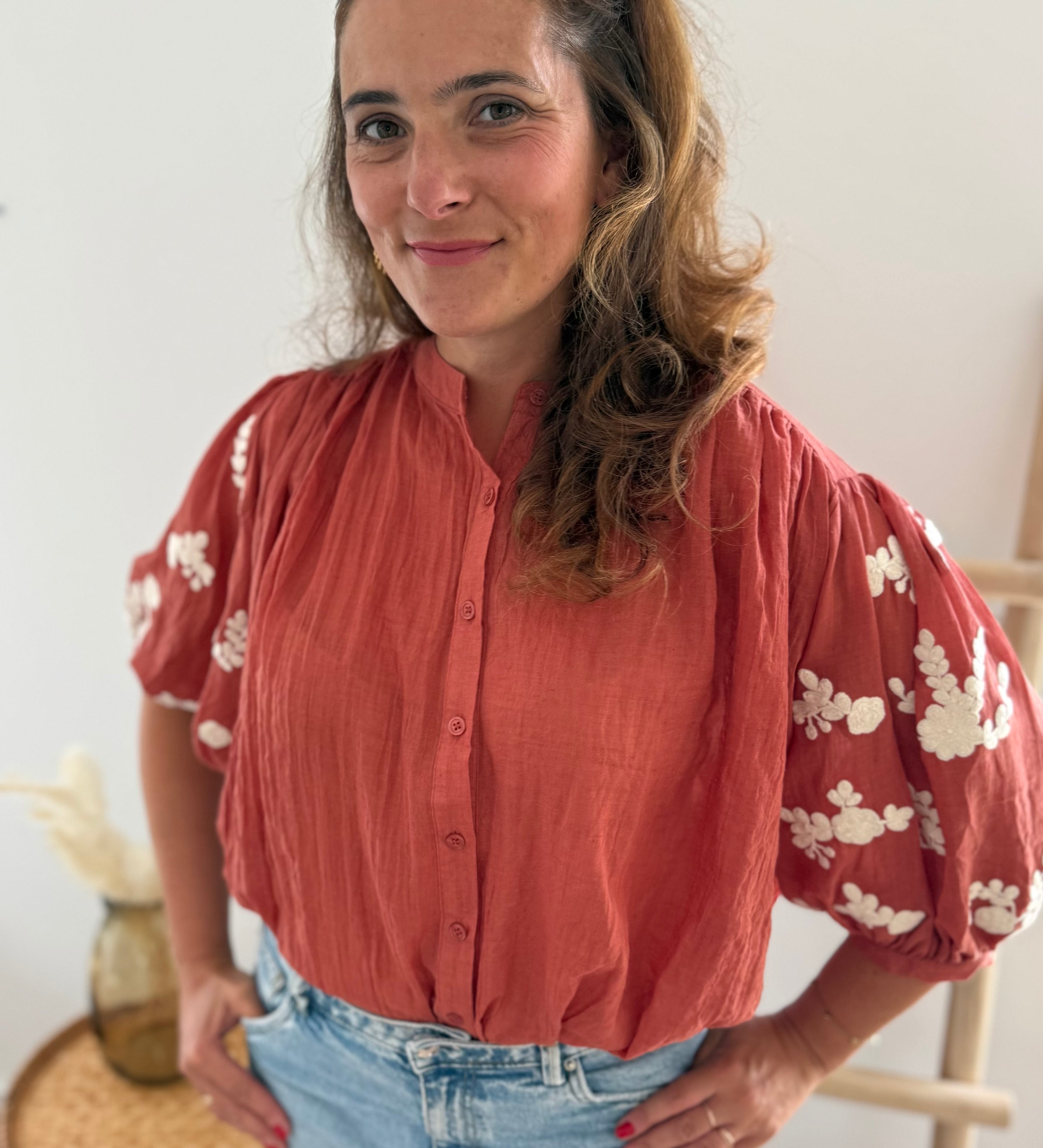 Leichte locker sitzende Baumwollbluse in rostrot mit beigen Blumenstickereien an den Ärmeln.