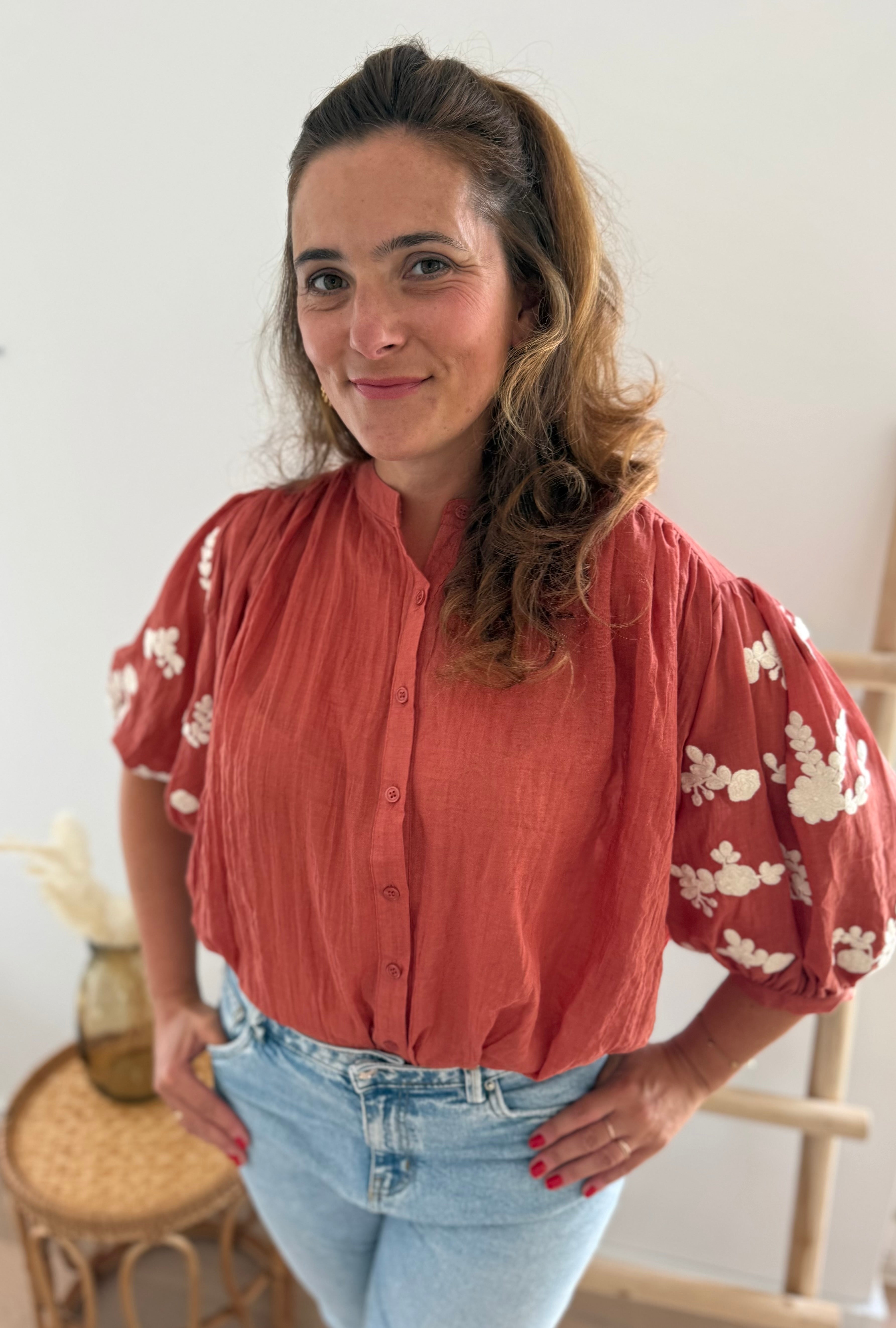 Leichte locker sitzende Baumwollbluse in rostrot mit beigen Blumenstickereien an den Ärmeln.