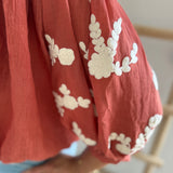 Leichte locker sitzende Baumwollbluse in rostrot mit beigen Blumenstickereien an den Ärmeln.