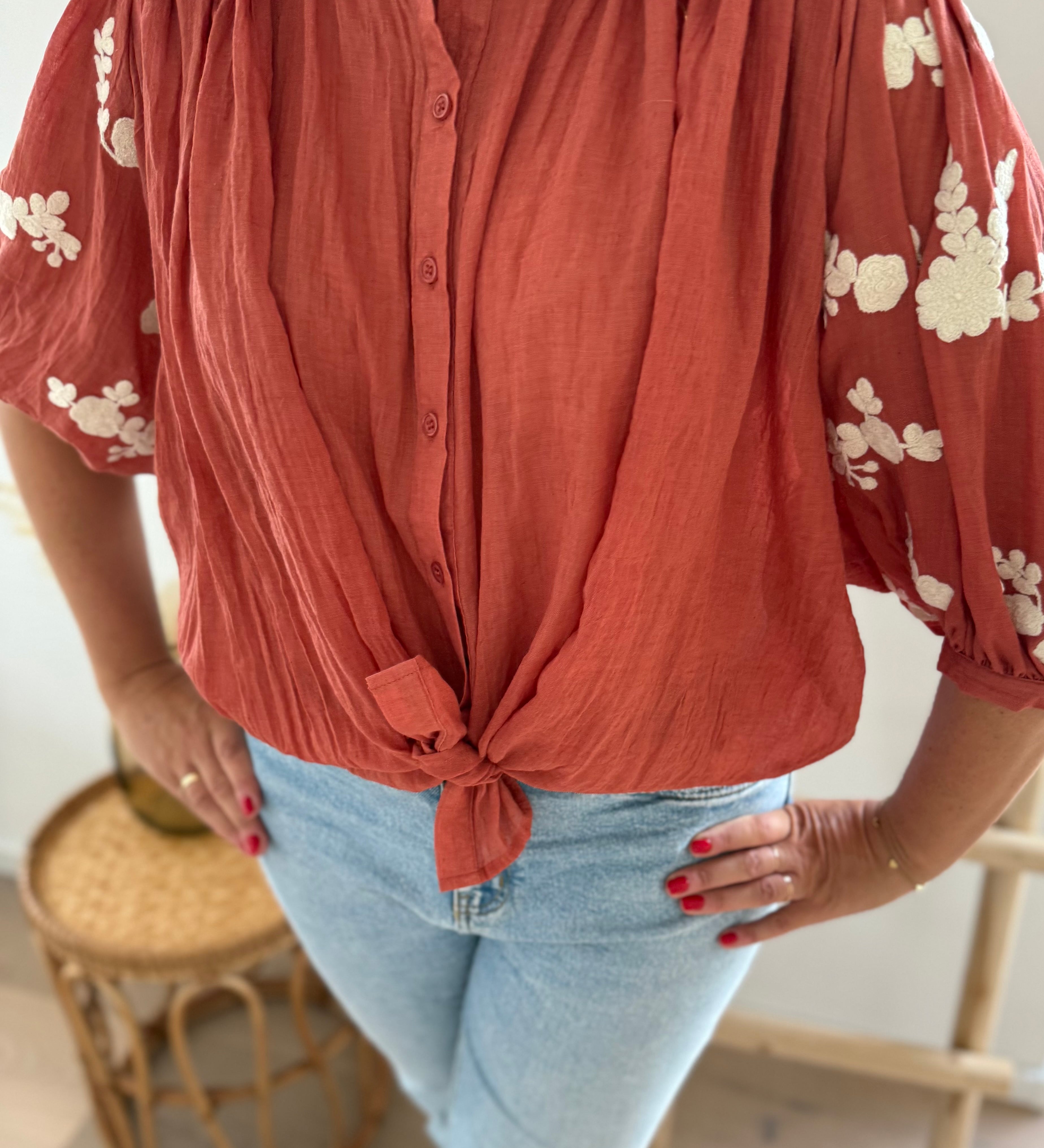 Leichte locker sitzende Baumwollbluse in rostrot mit beigen Blumenstickereien an den Ärmeln.