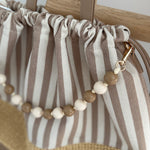 Gestreifte Tasche mit Bast am unteren Teil und einer abnehmbaren Perlenkette in den passenden Farben zu den Streifen. Farbe rosa beige.