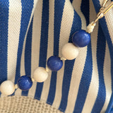 Gestreifte Tasche mit Bast am unteren Teil und einer abnehmbaren Perlenkette in den passenden Farben zu den Streifen. Farbe blau beige.