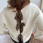 Strickpullover in beige mit Rundhalsausschnitt. Hinten wird der Pulli von Schleifen im Leoprint Muster zusammengehalten.