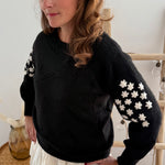 Schwarzer Strickpullover mit verspielten Blumenstickereien auf den Ärmeln in hellbeige.