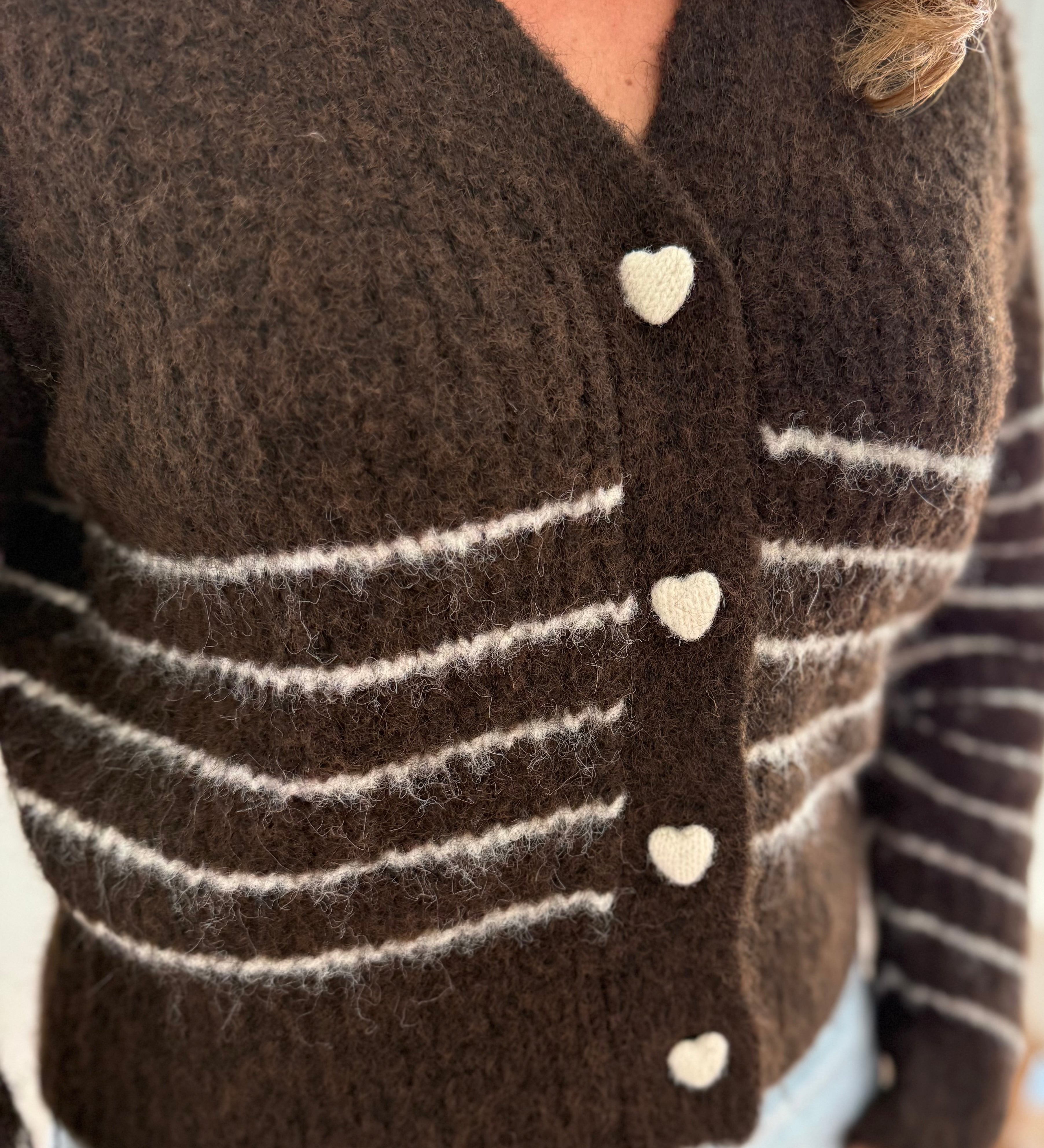 Kuschelige braune Strickjacke mit V Ausschnitt und weißen Streifen. Knopfleiste aus weißen Herzen.