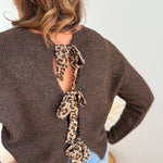 Strickpullover in braun mit Rundhalsausschnitt. Hinten wird der Pulli von Schleifen im Leoprint Muster zusammengehalten.