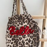Große Shopper Bag aus strapazierfähigem Denim Stoff. Tasche ist in Leomuster mit rotem "Bella" Schriftzug aufgedruckt.