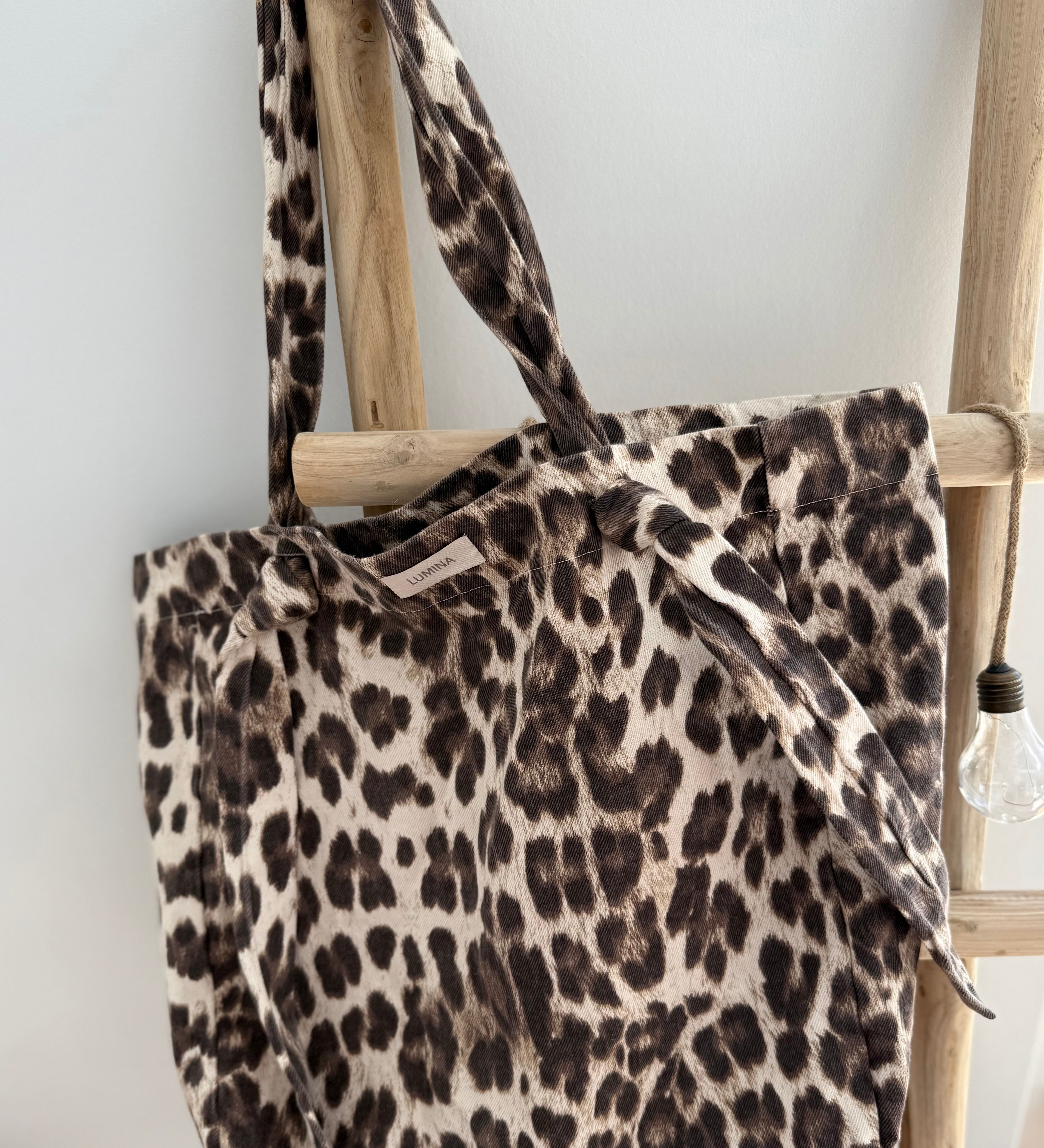 Große Shopper Bag aus strapazierfähigem Denim Stoff. Tasche ist in Leomuster mit rotem "Bella" Schriftzug aufgedruckt. Auf der Rückseite ist kein roter Schriftzug, sodass man die Tasche auch so herum tragen kann wenn rot gerade nicht zum Outfit passt.