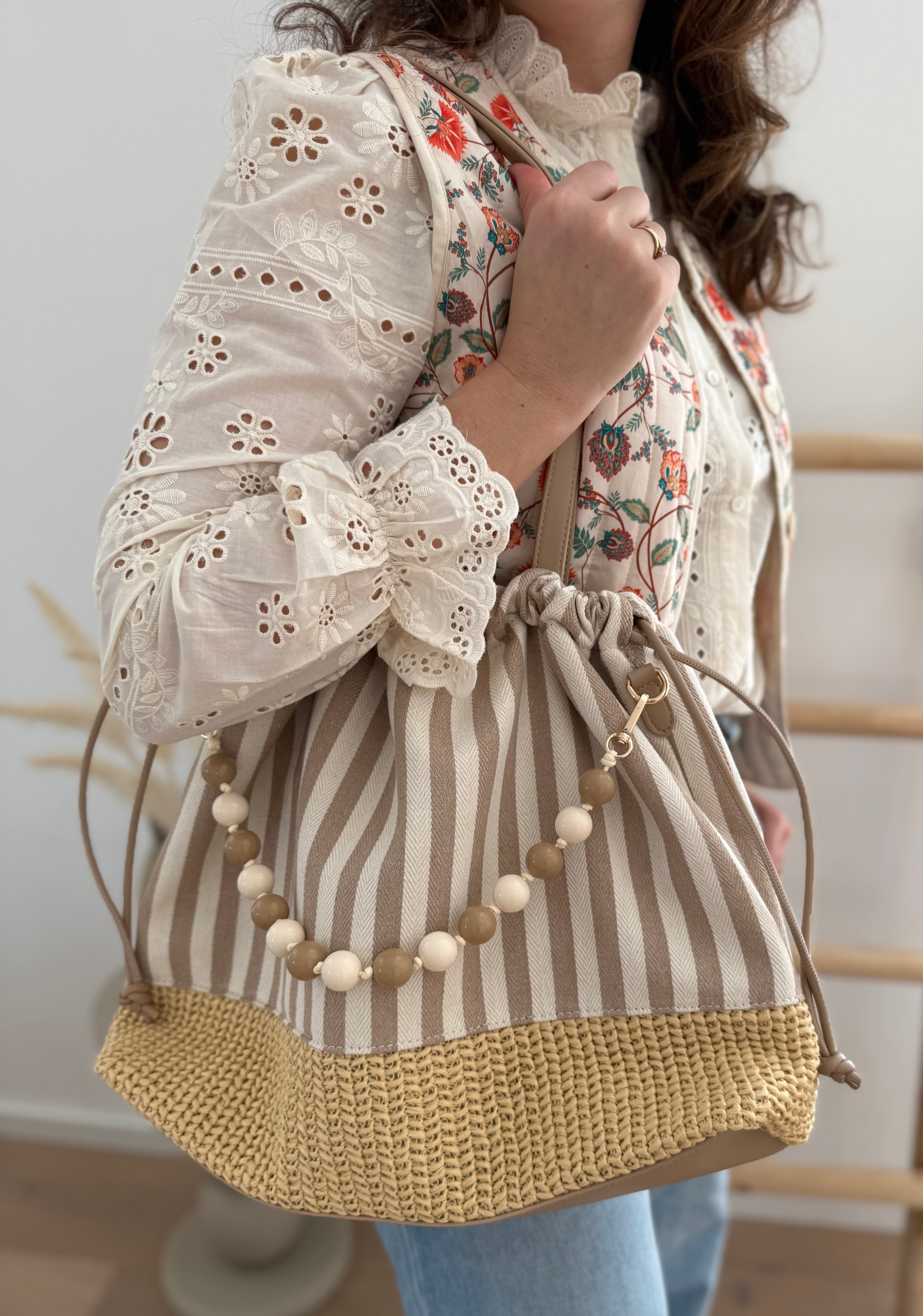 Gestreifte Tasche mit Bast am unteren Teil und einer abnehmbaren Perlenkette in den passenden Farben zu den Streifen. Farbe beige natur