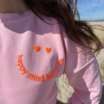 Locker geschnittenes Sweatshirt in rosa mit einem orangenen Smiley auf der Brust.