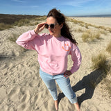 Locker geschnittenes Sweatshirt in rosa mit einem orangenen Smiley auf der Brust.