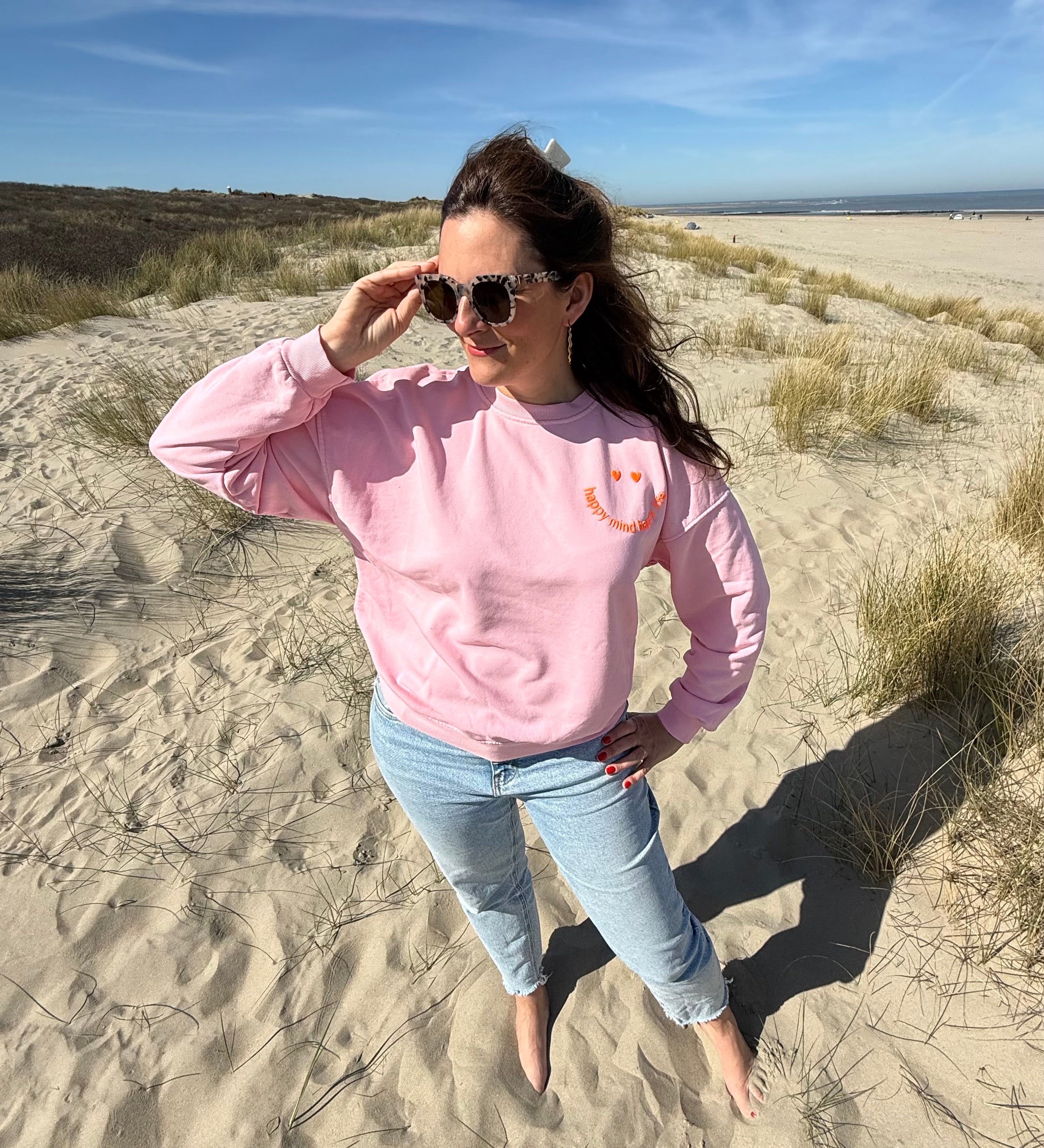 Locker geschnittenes Sweatshirt in rosa mit einem orangenen Smiley auf der Brust.