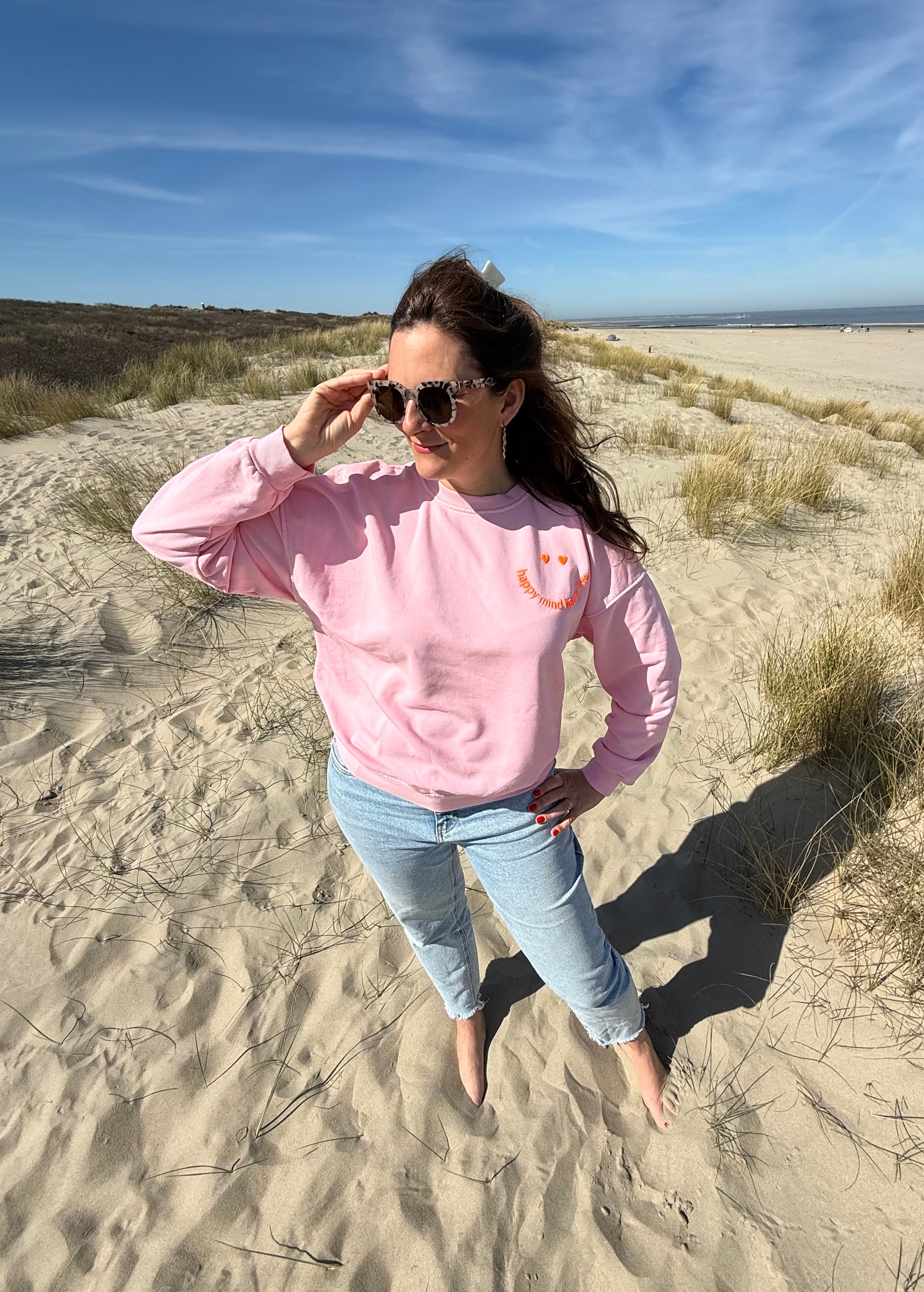 Locker geschnittenes Sweatshirt in rosa mit einem orangenen Smiley auf der Brust.