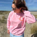 Locker geschnittenes Sweatshirt in rosa mit einem orangenen Smiley auf der Brust.