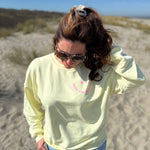 Locker geschnittenes Sweatshirt in butter yellos mit einem rosanen Smiley auf der Brust.