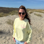 Locker geschnittenes Sweatshirt in butter yellow mit einem rosanen Smiley auf der Brust.
