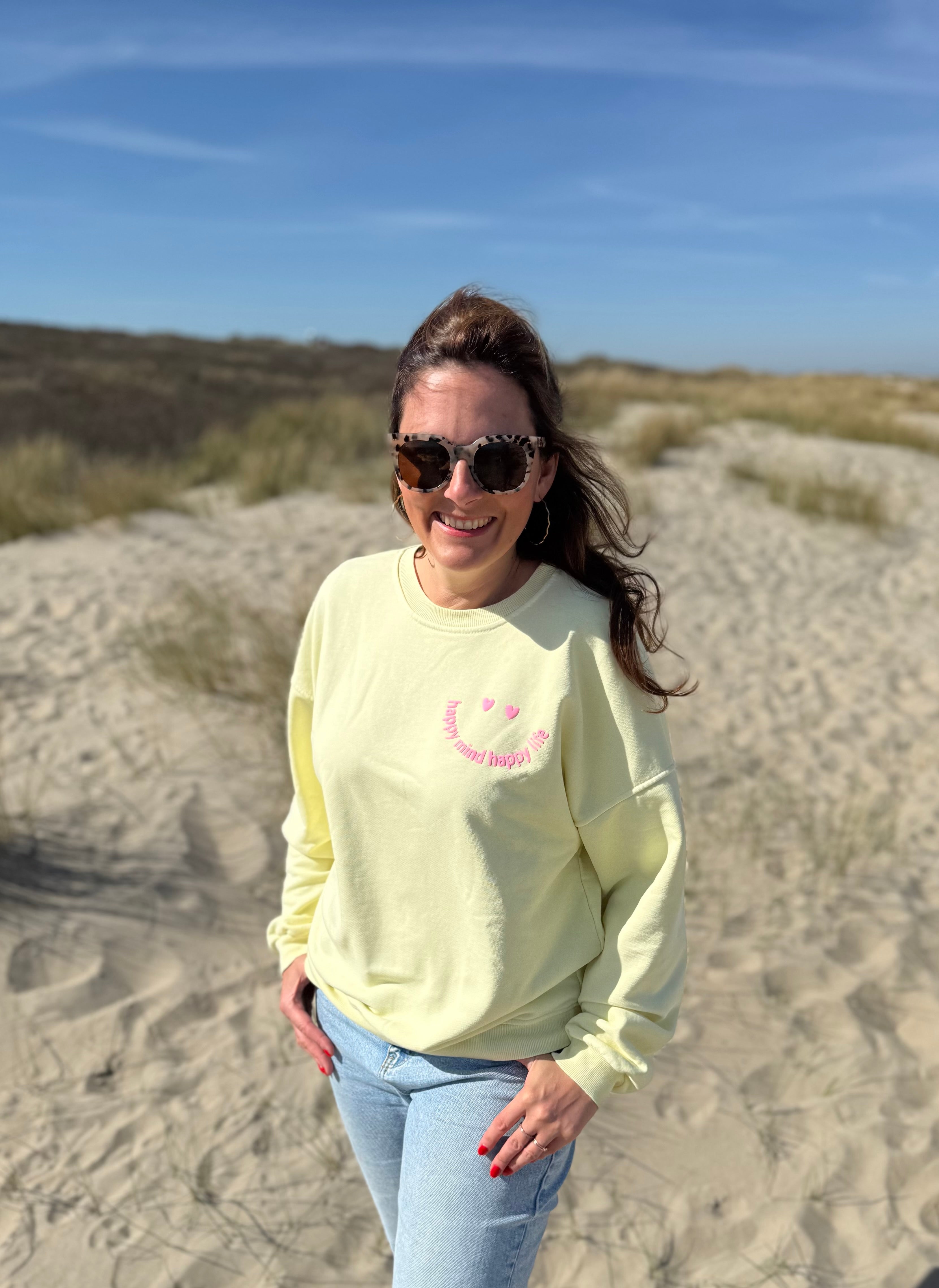 Locker geschnittenes Sweatshirt in butter yellow mit einem rosanen Smiley auf der Brust.