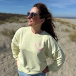 Locker geschnittenes Sweatshirt in rosa mit einem orangenen Smiley auf der Brust.