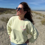 Locker geschnittenes Sweatshirt in rosa mit einem orangenen Smiley auf der Brust.
